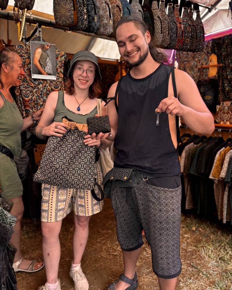 Couple at the SOL festival booth with a printed drawstring bag, pouch and pocket belt